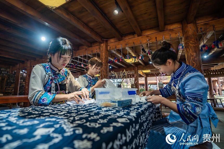 身着民族服饰的布依族姑娘正在制作布依族特色扎染手工艺品。人民网 涂敏摄