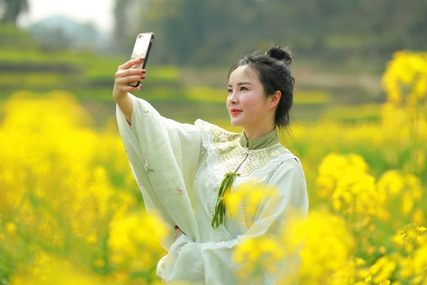 游客在油菜花田里自拍。