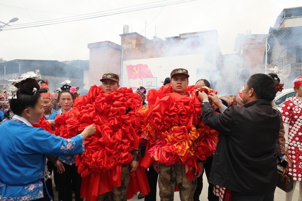 父母为新兵整理大红花。
