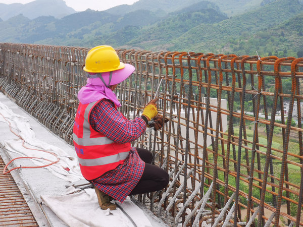 工人們在捆扎橋梁護欄鋼筋和澆筑混凝土。