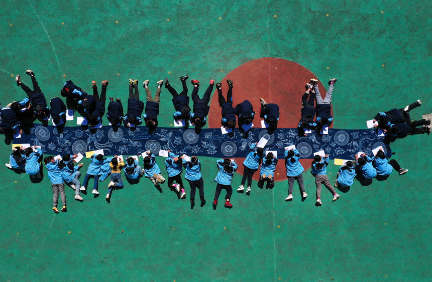 5月17日，小學生在貴州省丹寨縣龍泉鎮羊甲小學課后服務中學畫苗族傳統蠟染圖案（無人機照片）。