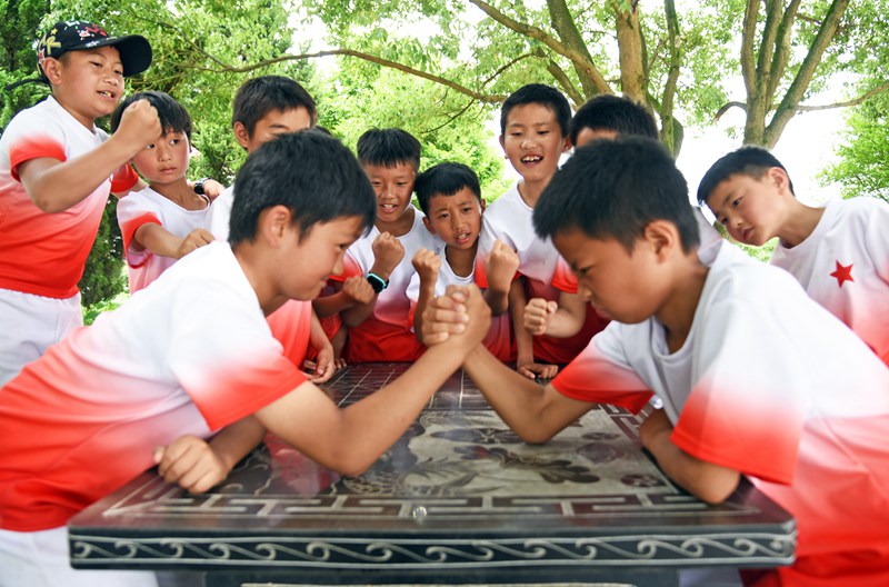 2022年6月1日， 在贵州省黔西市铁石苗族彝族乡铁石小学，小朋友们正表演扳手腕游戏。熊军万摄