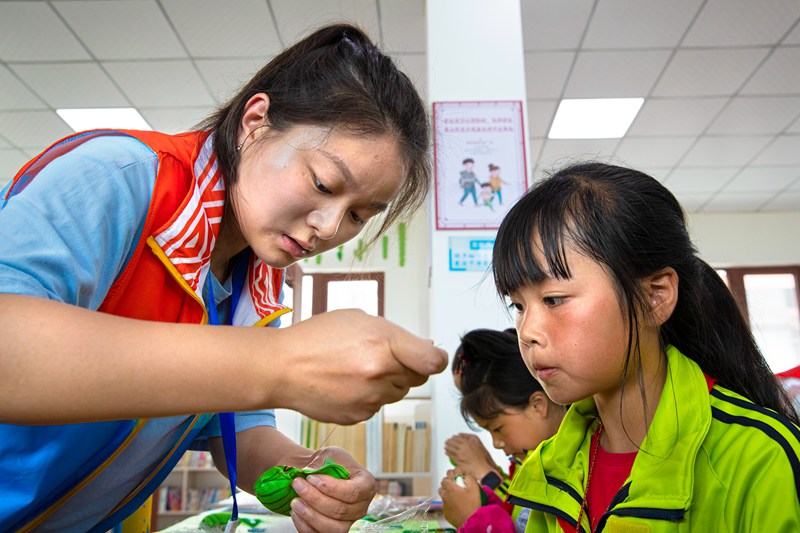 2022年6月2日，贵州省黔西市锦绣花都易地扶贫搬迁安置点，社会工作站工作人员指导搬迁群众的孩子手工制作香包。