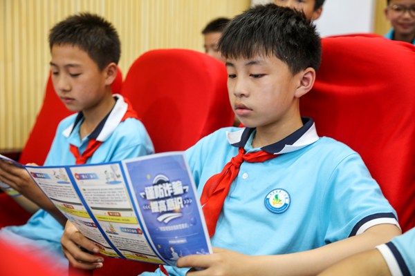 2022年6月15日，貴州省黔東南州施秉縣第一小學，學生在看預防養老詐騙宣傳手冊。磨桂賓攝