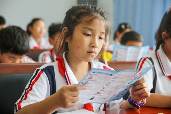 2022年6月15日，貴州省黔東南州施秉縣第四小學，學生在看預防養老詐騙宣傳手冊。磨桂賓攝