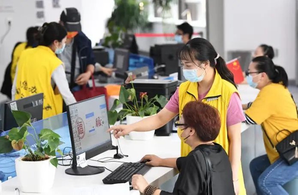 南明区政务服务大厅法人服务区的工作人员在自助帮办区域指导企业人员自主报税。