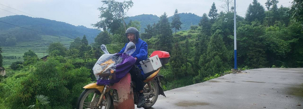 孫毅騎摩托車去農戶家給豬治病。