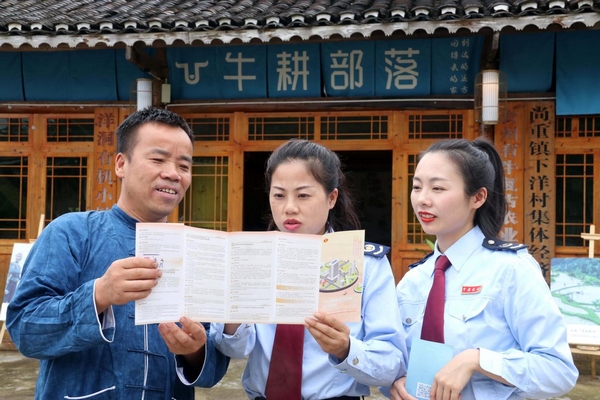 图为税务工作人员在向杨正熙宣传减税政策。