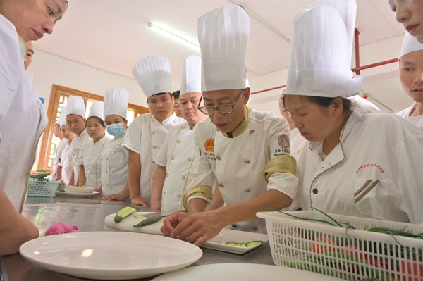 教师正在为参加职业技能培训的学员讲解菜品摆盘技巧。