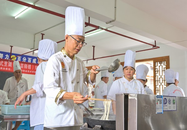 教师正在为参加职业技能培训的学员讲解烹饪技术。