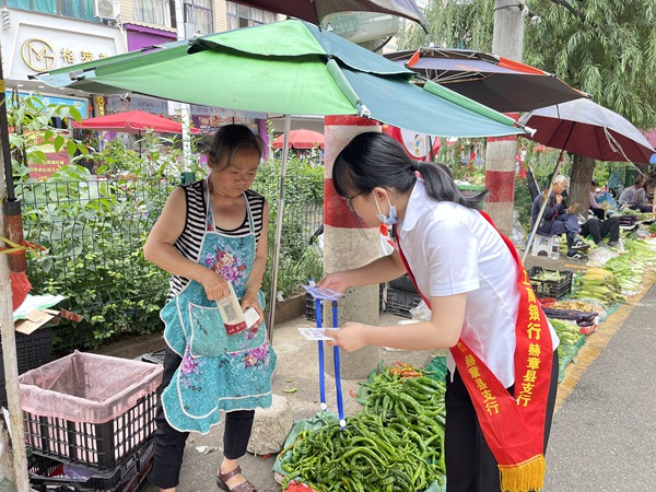 工行赫章支行工作人员为卖菜商户送去收款码，并耐心指导商户使用。图片由工行赫章支行提供