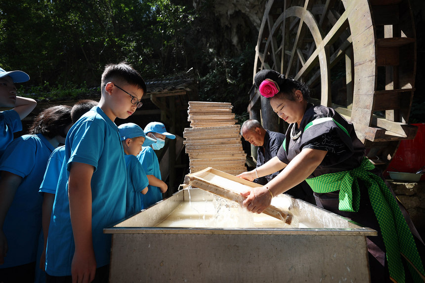 7月25日,小学生造纸作坊参观造纸工匠制作花草纸的流程。