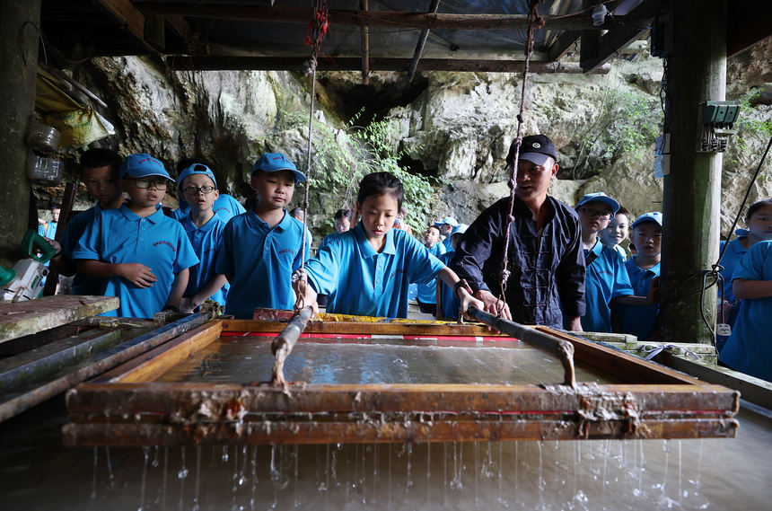 7月25日，小学生在造纸作坊体验古法造纸技艺。