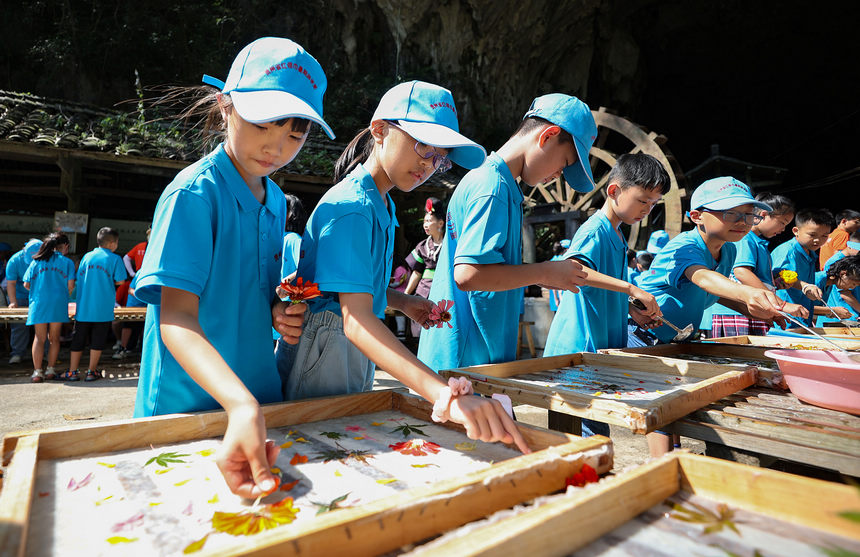 7月25日，小学生在造纸作坊体验花草纸制作技艺。