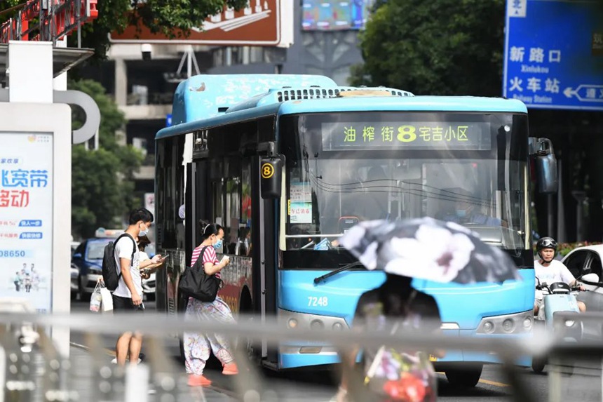 在钻石广场公交车站，乘客们自觉佩戴口罩，有序排队上车。
