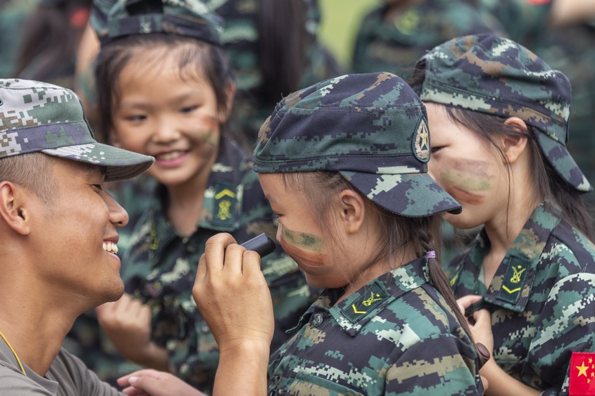 2022年7月28日，貴州省黔東南州施秉縣都市森林康養基地舉辦豐富多彩的軍事夏令營活動，教官在給孩子們畫迷彩妝。