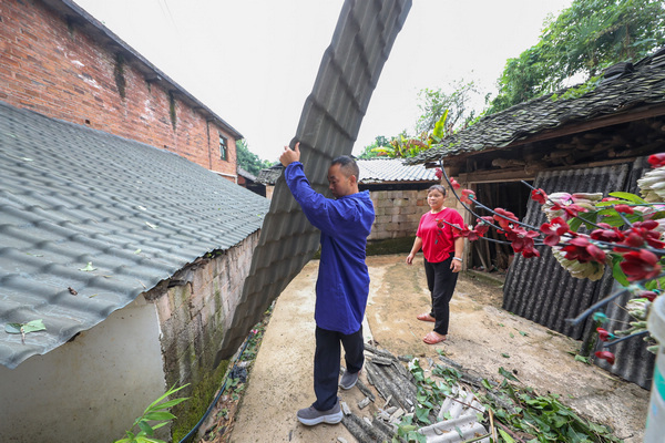 2022年7月28日，李朝富（左）杠材料帮助因大风受灾的村民修缮房屋。