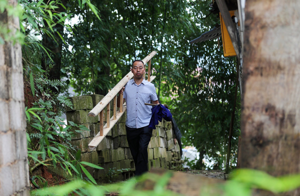 2022年7月28日，李朝富（左）扛楼梯准备帮助因大风导致受灾的村民修缮房屋。