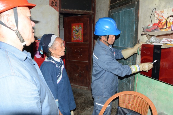 程勇、赵佳明为杨光秀老人检查家里的电器。