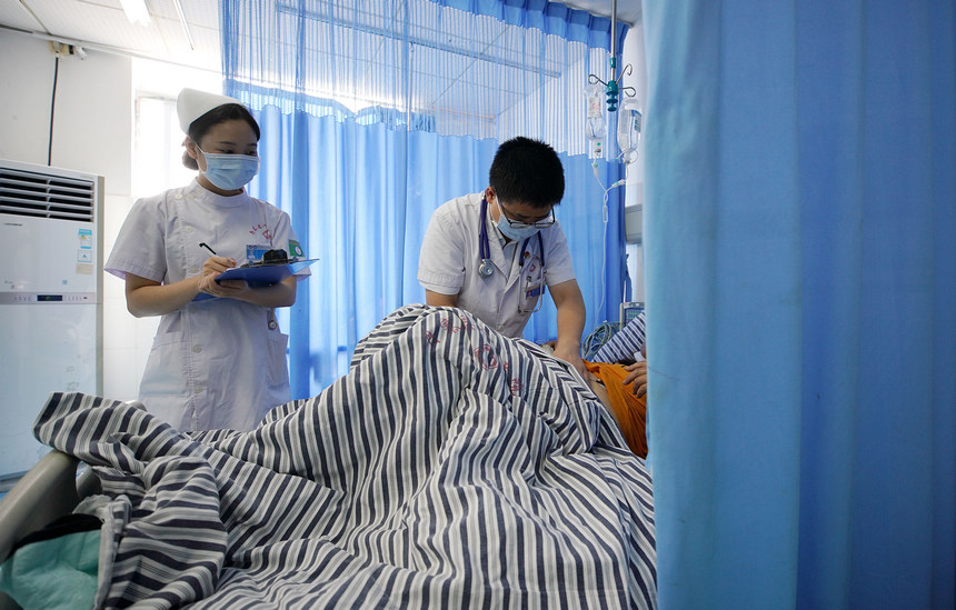 8月18日，丹寨县人民医院病房外科医师（右）为患者做检查。