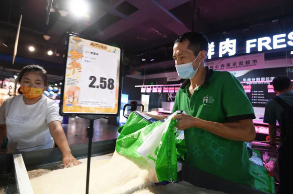 南明区惠民生鲜合力超市南浦路店工作人员正给大米专柜加货补货。