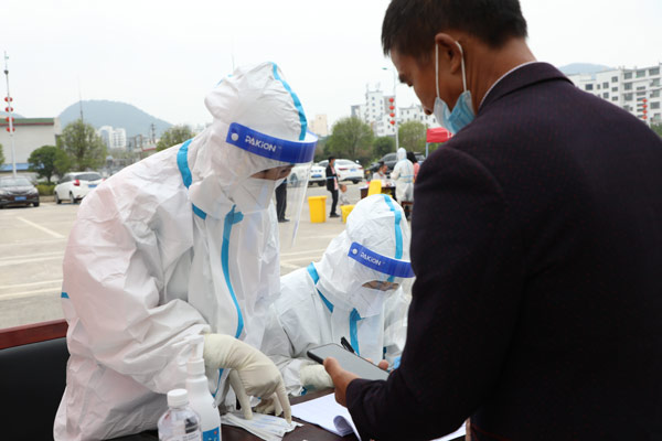 医务人员在广顺镇金竹花园社区核酸采样点帮助群众登记信息。