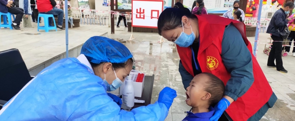 志愿者协助幼儿园孩子做核酸检测。