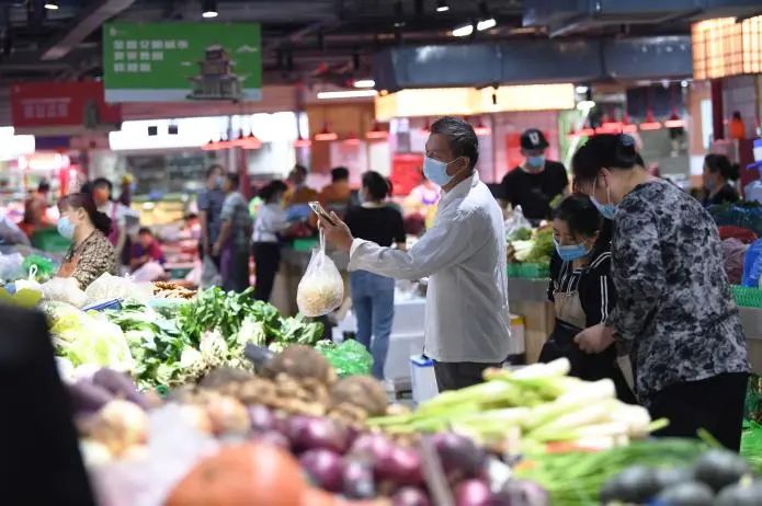 居民在新路口农贸市场内购买蔬菜。