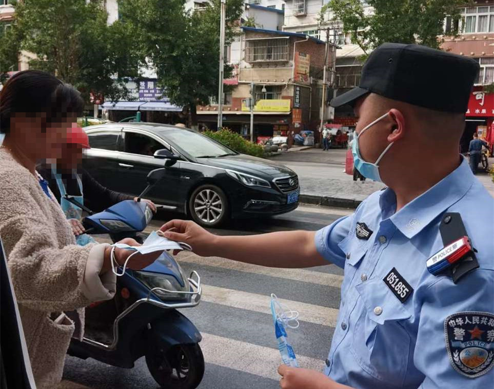 圖為民警向街面未佩戴口罩群眾分發口罩。