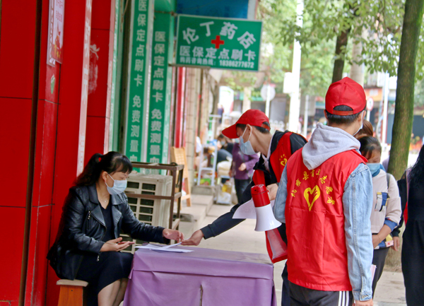 2022年9月13日，納雍縣城，志願者在給商鋪負責人發放疫情防控宣傳資料。