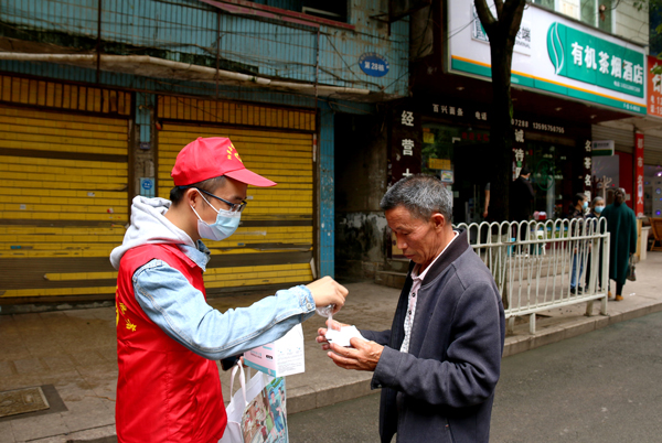 2022年9月13日，纳雍县城，志愿者在向未戴口罩的市民发放口罩，并要求戴上 。