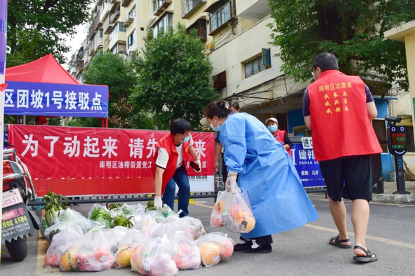 居委會工作人員和社區志願者對物資進行消毒接收后，分發到居民手上。