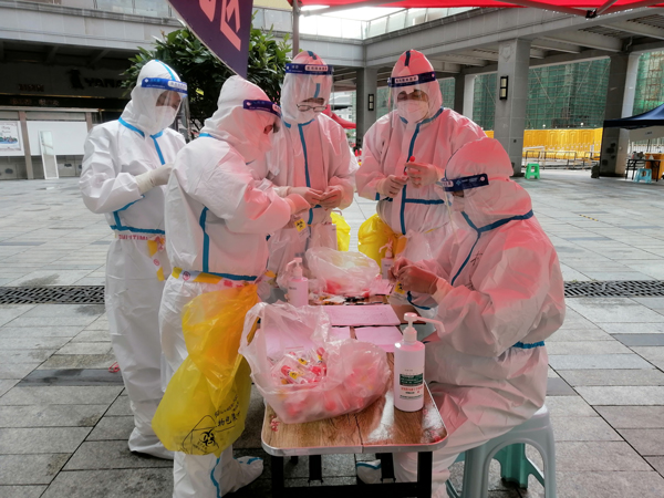 杨光亮与医生、志愿者一道收集整理核酸检测样本（右：坐凳子者）。