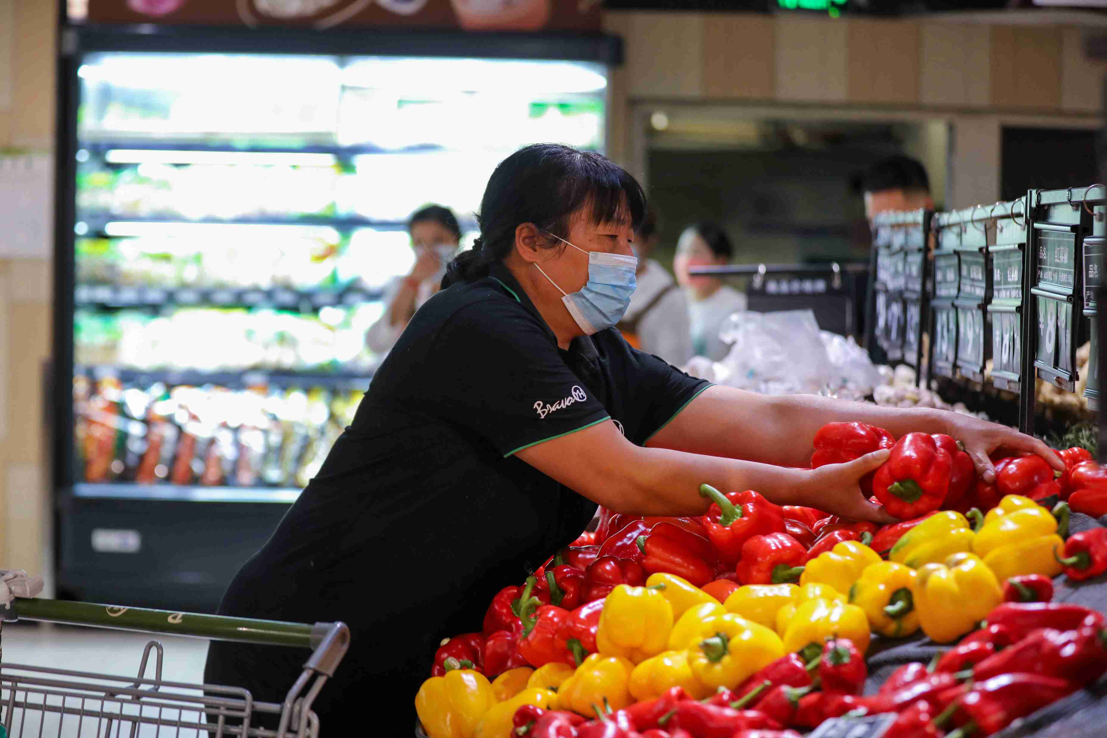 永輝超市工作人員正在擺放蔬菜。