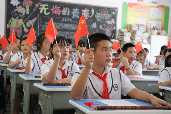 玉屏侗族自治县印山民族小学学生正在挥舞小红旗。