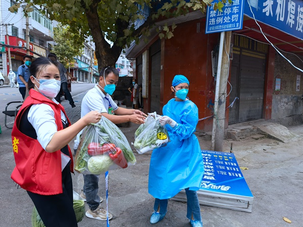 社區工作員將蔬菜包移交志願者。