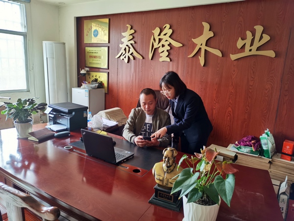 插图1:客户经理指导企业主使用邮储银行手机银行申请贷款。