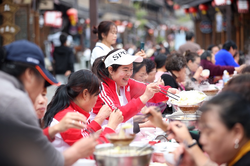 10月31日，游客在丹寨县万达小镇长桌宴上品尝当地美食。