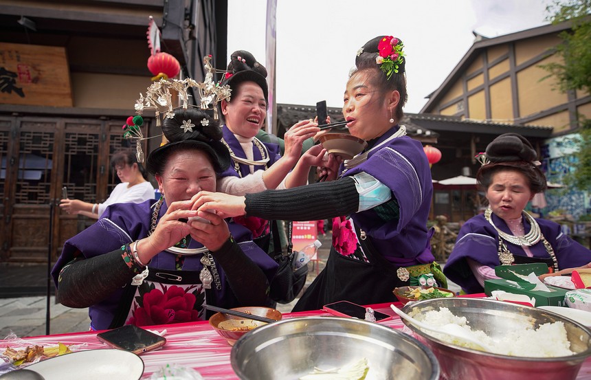 10月31日，在丹寨縣萬達小鎮，身著節日盛裝的苗族同胞在長桌宴上相互敬酒菜。