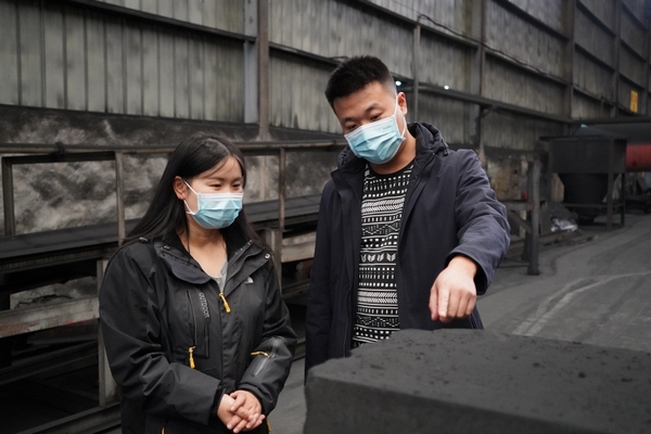 贵州省兴隆碳素有限公司负责人邹济龙（右）向记者介绍公司生产的碳块产品。