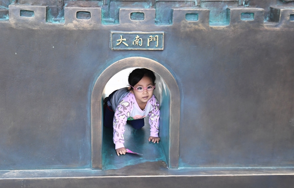 11月4日，一小朋友正爬行穿過貴陽市南明區青雲路步行街青雲門雕塑中的大南門。