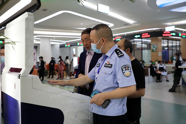 图为民警在指导办事群众使用自助终端办理交管业务。