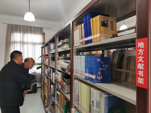 陈福来在大方县图书馆地方文献书架浏览图书。