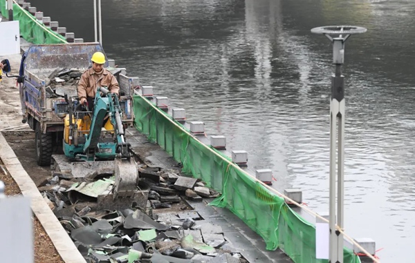 1工人正在拆除河道旁老舊破損跑步綠道。