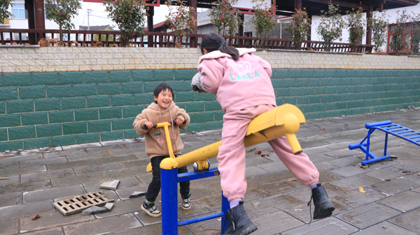 杨家湾镇松山村孩子们正在广场上玩跷跷板 。