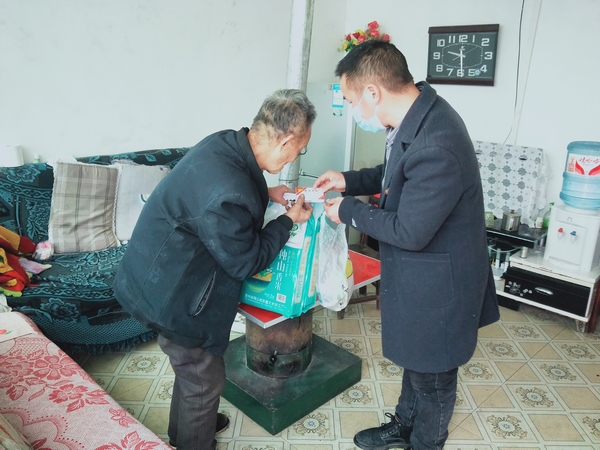 图2:平寨村党员干部为村民向元斌讲解药品的服用方法。