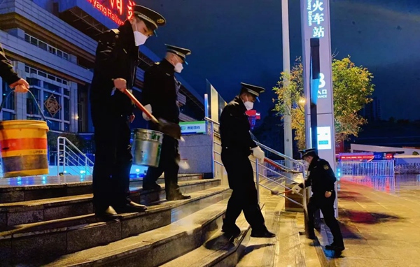 圖片12月27日晚11時05分，區城市綜合行政執法局的執法隊員在貴陽火車站台前廣場撒鹽除冰。