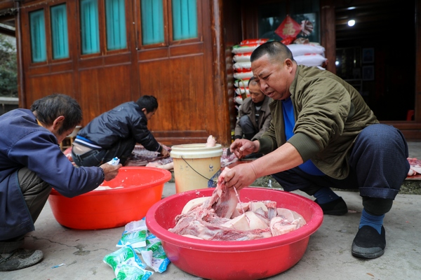 杨志福（右）给抹好盐的猪肉串绳子。