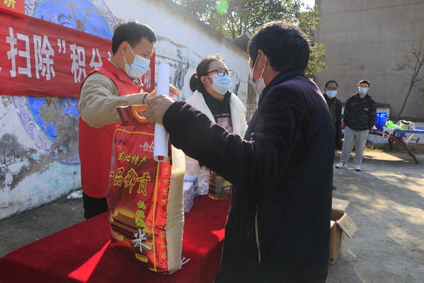 图1：乡文化中心副主任姜骄炜正在给志愿者放发生活用品