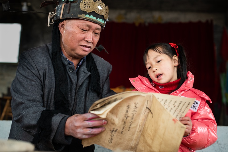 天柱县平甫村侗戏班老戏师在教小演员学习剧本。